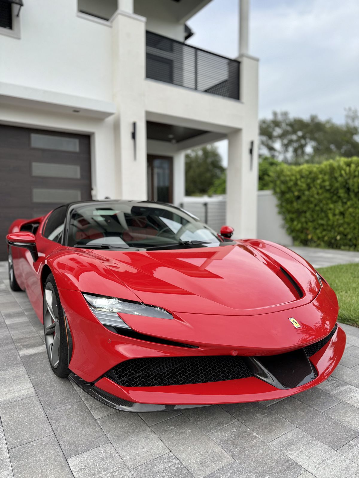 Red Ferrari SF90 at a modern villa