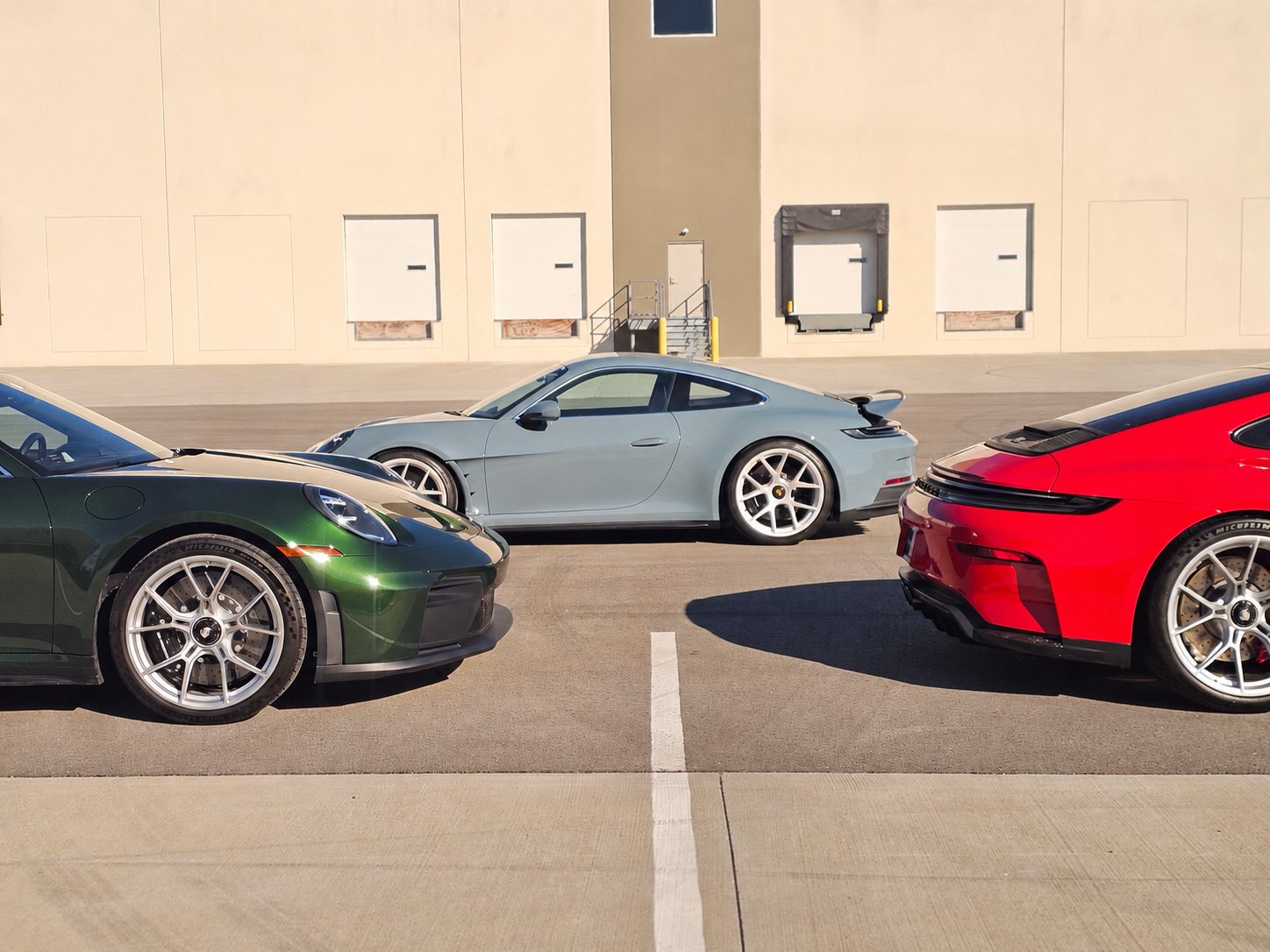 Three Porsche 911 GT3 sports cars staged at a warehouse before transport