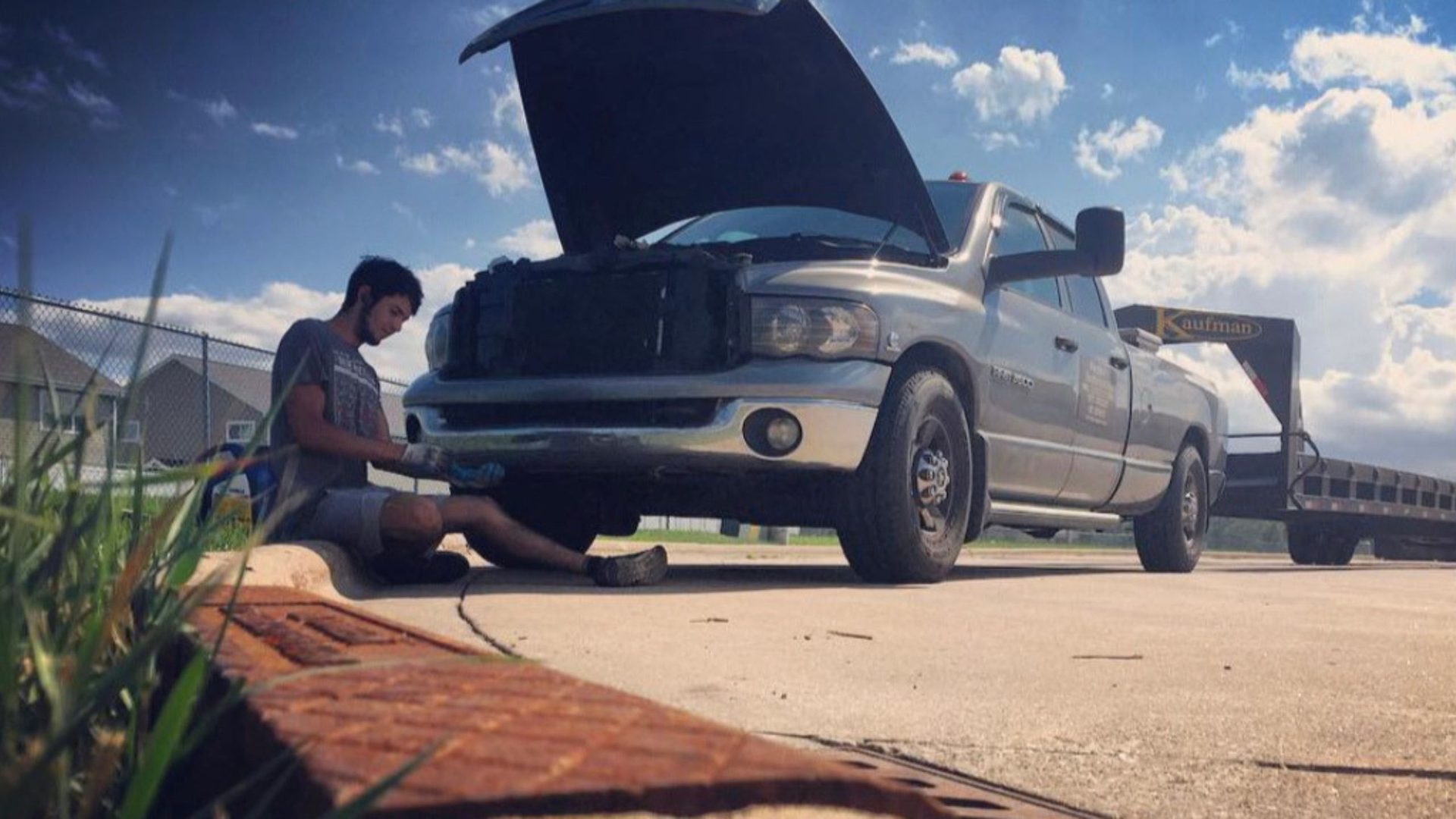 Driver working under the hood of a hauler truck on the road